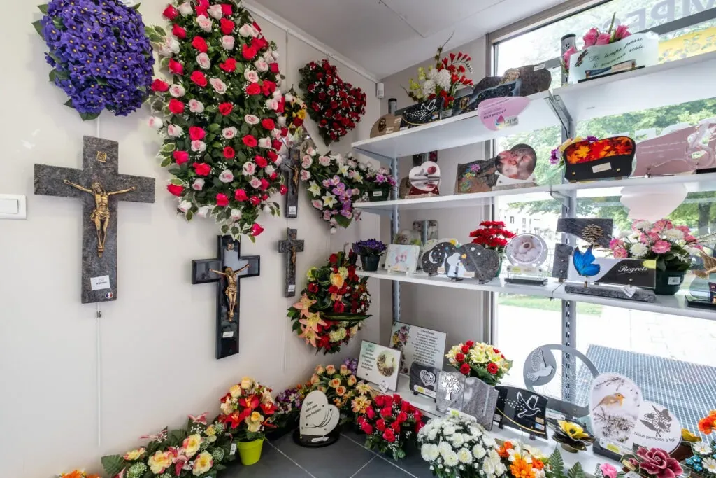 Espace de vente présentant des plaques funéraires, des croix murales et des fleurs.